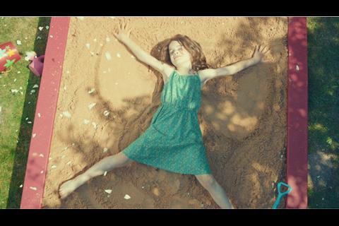 The ad shows a girl making 'snow angels' in the sand